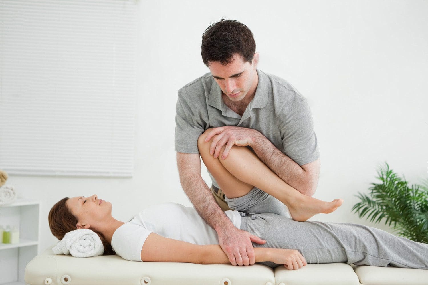 stock photo brown haired woman being stretched by a man in a room