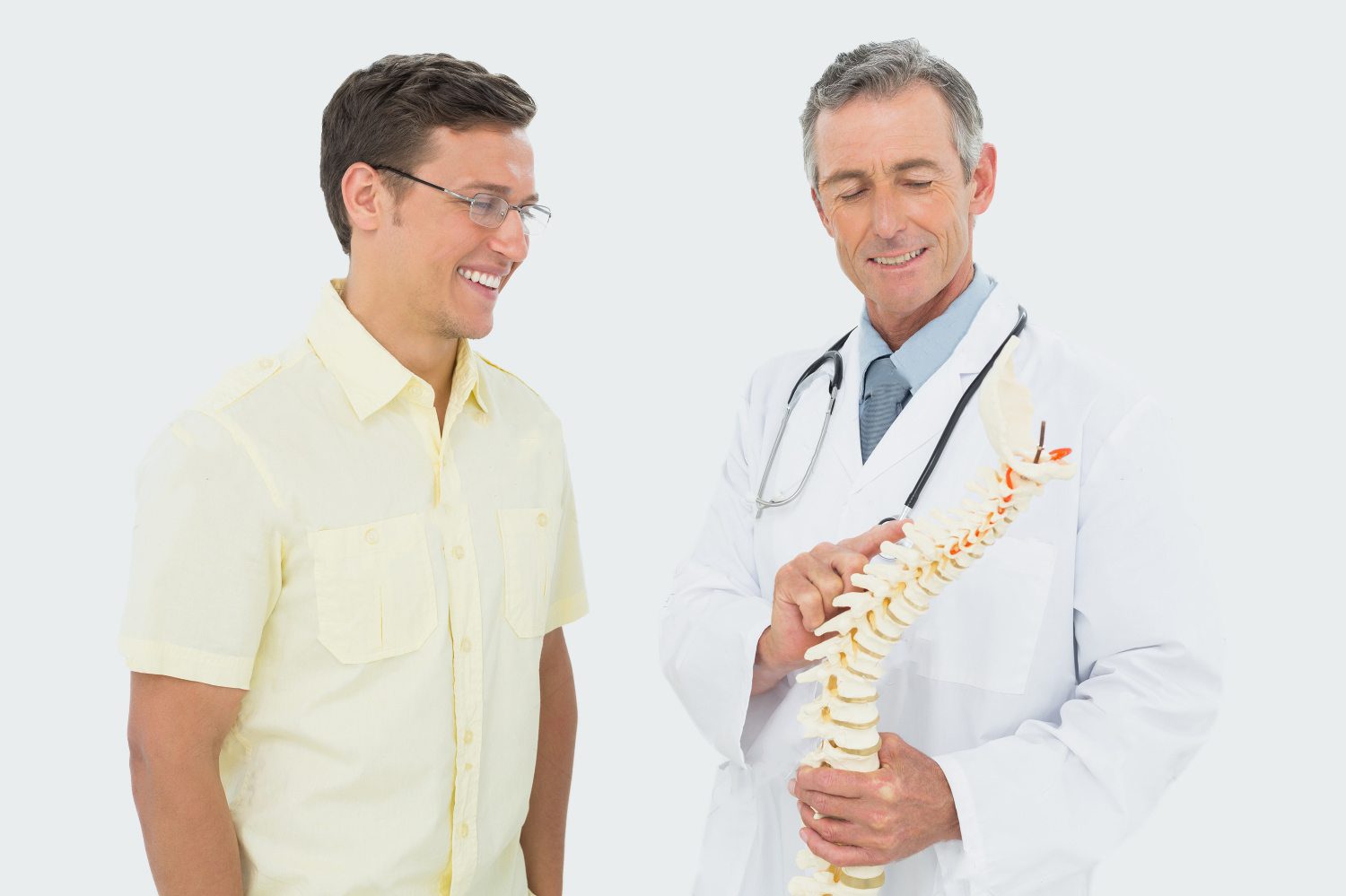 stock photo smiling male doctor showing patient something on skeleton model over white background