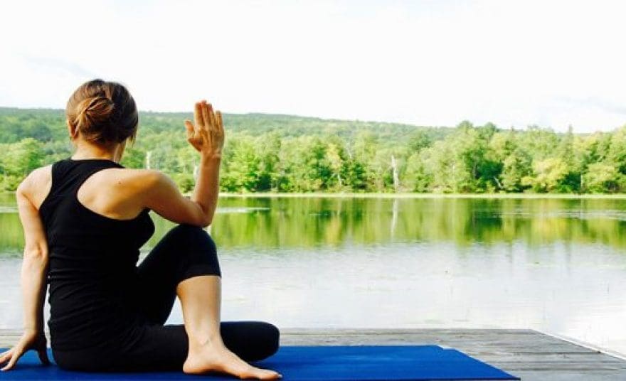blog picture of woman doing yoga by lake