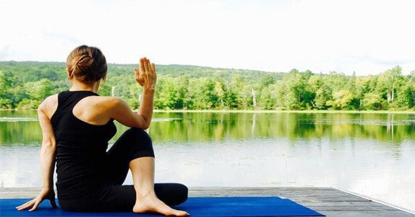 blog picture of woman doing yoga by lake